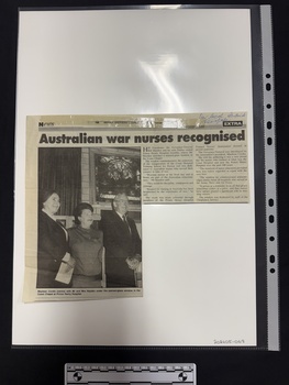 Clipping of article with a large black and white photograph of two women and a man standing in front of a stained glass window.  Article has two columns of text and the details of the publication are sticky taped to the top of the clipping.