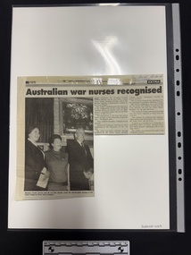 Clipping of article with a large black and white photograph of two women and a man standing in front of a stained glass window.  Article has two columns of text and the details of the publication are sticky taped to the top of the clipping.