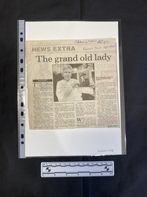 Newspaper clipping of four columns of text with a centred black and white photo of an older woman