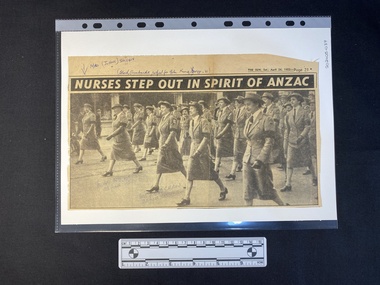 A newspaper clipping of a title above a large black and white photo of a large group of women in uniform
