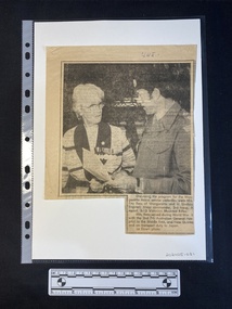 A newspaper clipping of a large black and white photo and a caption