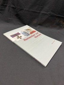 Grey and white paperback book with maroon and white writing on cover and spine. Cover also has images of a medal, uniform and portait of a woman in army nurses uniform.