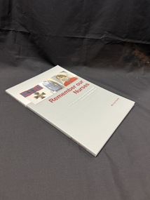 Grey and white paperback book with maroon and white writing on cover and spine. Cover also has images of a medal, uniform and portait of a woman in army nurses uniform.