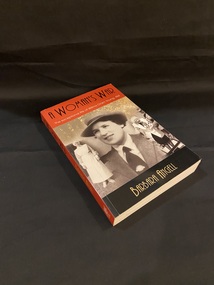 Paperback book with a maroon coloured spine that shows the title printed in black and the author's name printed in gold. The front cover shows a large image of Nurse Wilma Oram Young in uniform when she was a young lady with hat and tie, in the background to the left is an image of Wilma in full nurses attire and to the right is an image of her as an older lady wearing medals and being supported by a soldier in uniform. There is a black strip along the bottom of the front cover with the author's name printed in gold. Along the top of the cover is a maroon strip with the title and subtitled printed.