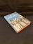 Hardcover book with dust jacket. The dust jacket is light blue with the title printed in white and the author and sub title printed in red. The front cover has the author's name at the top followed by the title in large lettering.  The sub title is beneath in smaller writing. The lower half of the cover shows a black and white image of three female nurses in uniform, happily walking arm in arm.