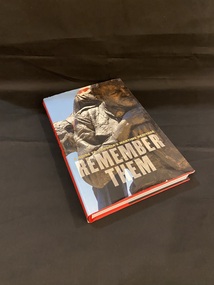 Red hardcover book  with a dust jacket. The dust jacket has a red spine with the title in black writing and the sub title in gold writing. The front cover shows a close up image of a bronze statue of a soldier carrying another soldier on his back and looking very solemn At the bottom of the cover reads 'A guide to Victoria's wartime heritage' in gold, and 'Remember them' printed in cream text.