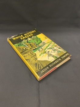 Hardcover book with a dustjacket firmly attached. There is a black panel across the top with the title in yellow print and another thinner black panel across the bottom with the author's name in cream coloured print. The front cover shows an illustration of a Japanese soldier in the foreground and behind him are eight women working in a field, they are being watched by an armed soldier stationed at a lookout on a wall behind them. The image is in black, green and yellow.