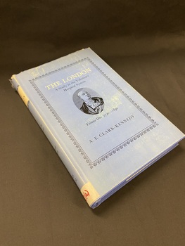 Hardcover book with a blue dust jacket. The dust jacket has an ornate black border surrounding the title and author information and in the centre is a black pen drawing of a man in an oval template. The spine has a cream coloured box at the top with 'The London' printed in black.