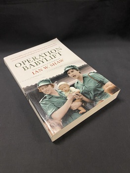 White book with a picture of two women in green uniforms, one of whom is holding a baby, in front of a building with a corrugated roof. The title 'OPERATION BABYLIFT' is printed above the image in green, followed by the author's name in red text. At the top of the page it reads "The incredible story of the inspiring Australian women who rescued hundreds of orphans at the end of the Vietnam War".