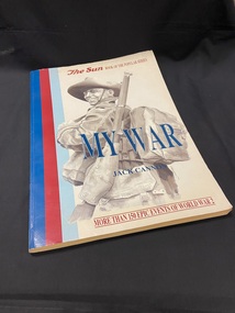 Large paperback book with a blue,red,light blue stripe running vertically down the left side, an image of a soldier covering most of the cover and the title and author in blue text across the middle.