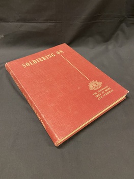 Maroon cloth bound hardcover book with title in cream print across the top, a straight line running vertical down the right side, below which is the Australian Commonwealth Military Forces emblem and the words 'the Australian Army at home and overseas'.