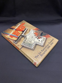 Light brown cover and spine. The title is printed diagonally near the top of the cover in red print, with the author's name above that in white print. At the bottom of the cover is the sub-title in black print. The background of the entire cover is a close-up image of the fabric of a soldier's uniform with a bullet wound and a silver medallion that reads 'Tobruk siege 1941'.