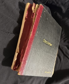Bound hardback book with black and red cover with gold lettering, spine is red, back cover missing.  Book is damaged.