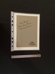 Thin, olive green booklet with two staples in the spine. The title is printed in brown ink on a slight diagonal angle towards the top of the cover. There is the Australian Commonwealth Military Forces emblem in the bottom right corner, also printed in brown ink.