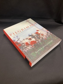 Cover has a red spine with white and balck text. The front cover shows red rose bushes with a faded building in the background. The title is printed towards the top of the page in red print, with the sub-title just below it in black. At the bottom of the cover is the author's name printed in white.