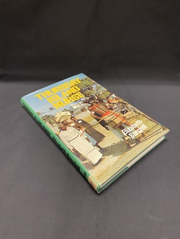 Hardcover book with dustjacket. It has a green spine with black writing. The front shows a photographic image of a re-enactment of "The coming of light" (an annual commemoration of the arrival of the first missionaries on Thursday Island). The title is printed in large yellow letters across the top.
