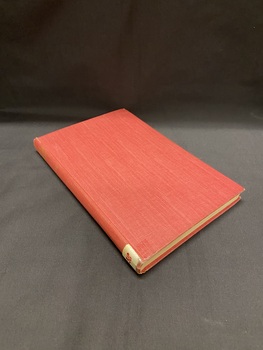 Faded red hard covered, cloth-bound book with gold title on the spine and a white sticker at the bottom of the spine with B38 in red texta.