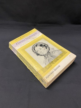 Worn paperback book with several pieces of old tape stuck across the cover. Yellow and white cover with an illustrated portrait of Florence Nightingale in a square frame in the centre. The title and author are printed in black at the top of the cover.