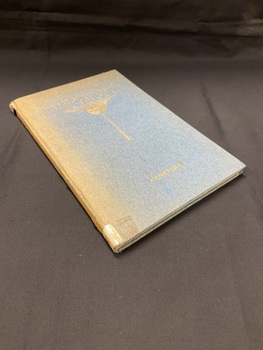 Blue hardcover book with extremely faded spine and cover. Australian War Memorial is printed in gold print across the front, followed by a gold sword symbol and 'CANBERRA' is printed across the bottom.