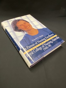 Blue and white dustjacket. White spine with a block of dark blue across the centre and the title printed in white text. The front cover shows a photo of a smiling nurse in a blue nurses top; the title and author are printed in a dark blue panel across the bottom.