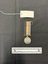 Photo of the reverse view of the Australia Service Medal. Made from nickel-silver, the reverse has a central and textured design of the crowned effigy of King George VI, facing left and signed 'PM', the initials of designer Percy Metcalfe, below the truncated neck of the effigy. Around the perimeter is the legend 'GEORGIVS VI D:G:BR:OMN:REX ET INDIAE IMP:' The ribbon is tactile, feeling ribbed under finger. This photograph is taken upon a black background, with a scale card and object number included.