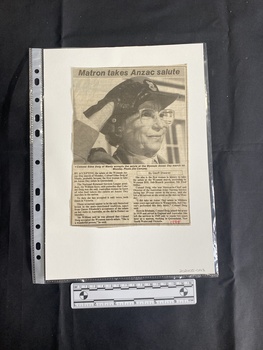 A newspaper clipping featuring a large black and white photo beneath a title and above two columns of text