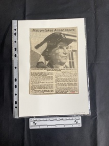 A newspaper clipping featuring a large black and white photo beneath a title and above two columns of text