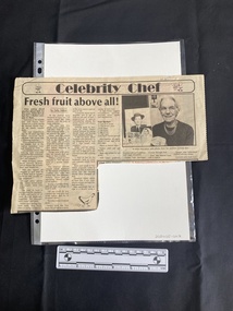 A large newspaper clipping of a seven column story, with titles and a black and white photo above