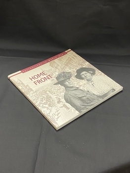 Square shaped paperback book with a sepia toned, faded image of a military parade down a city street lined with people. The image wraps around both covers and the spine. Title printed in burgundy print along the spine. The front cover has a black and white image in the foreground of a soldier standing with an older woman. There is a burgundy text box across the top with the sub-heading printed inside.