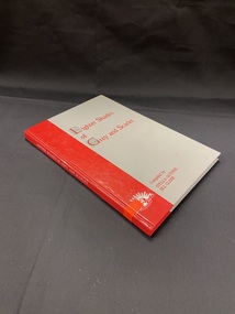 Grey book with a red vertical block down the left side that continues around the spine. The title is printed in red text on the front. There is a bright orange sticker near the lower part of the spine.