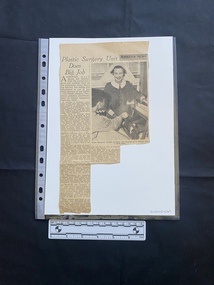 A newspaper clipping with a large column of text, a small column of text and a large black and white photo