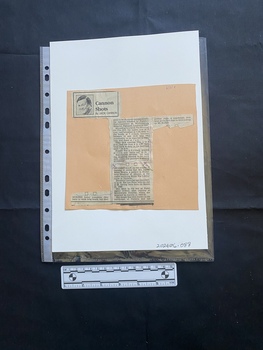 A newspaper clipping in two parts stuck to a piece of card, consisting of three columns of text and a black and white headshot