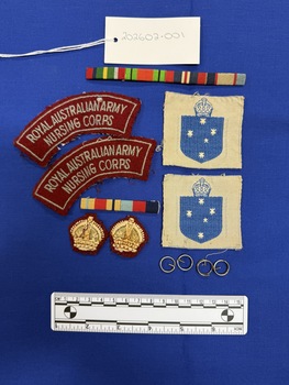 Two sets of ribbon bars with coloured stripes that indicate awards received, three sets of two patches including maroon battledress flashes, blue and white southern command formation sign patches and maroon and gold rank patches, along with four metal split rings.