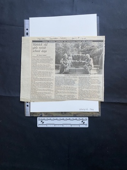 A large newspaper clipping with a title, subtitle, byline, three columns of text and a large black and white photo