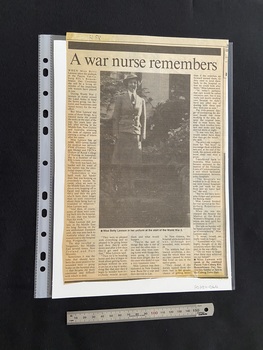 Large article cut from a newspaper page. Title across the top with five columns of text below. The left and right columns run the full length of the page. The middle columns are quite small and above them is a large photo image of a nurse in uniform.