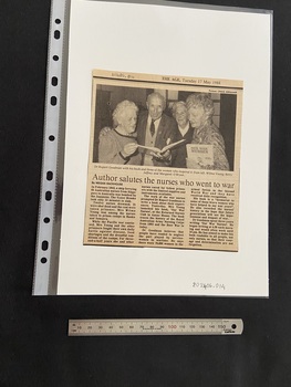 Newspaper clipping with publication title and date at the top and a photograph above three columns of text. Black and white photograph is of three older women and one older man holding copies of a book in their hands.