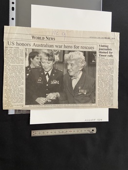 Half a newspaper page with two articles, the date and paper are printed across the top right, with 'World News' on the line below. The main article takes up most of the page with one column of text and a large photograph of Major Beverly Jorgenson escorting Jean Allen.