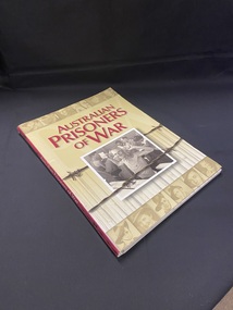 Spiral bound book with cover that wraps around the binding. Maroon spine with title printed in cream and barbed wire either side. The cover shows a strip of sepia toned portraits of soldiers across the top and bottom of the page. The title is in large maroon lettering and a photo of an emaciated prisoner in a mess hall, is below, with barbed wire running across and behond the photograph.
