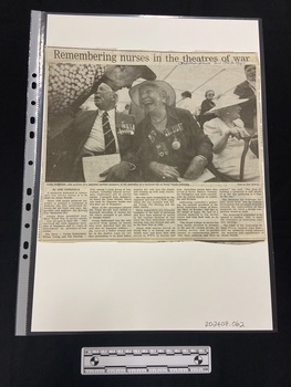 Large newspaper clipping featuring a large photograph of multiple people gathering beneath a marquee, followed by five columns of text.
