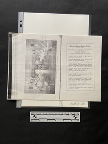Photocopy of pages from a book that has been copied in landscape orientation to show two pages on one sheet of paper. 
The left side page is a black and white photo displayed sideways of a hospital ward. There is a row of 5 beds along both side walls and a large space in the middle with a small table holding a flower arrangement. Eight of the beds have patients sitting up smiling towards the photographer, there are also five nurses standing beside various beds.
There is a bold black line down the middle of the page and on the right there is a rectangle border around a heading and eleven short paragrphs of black print.