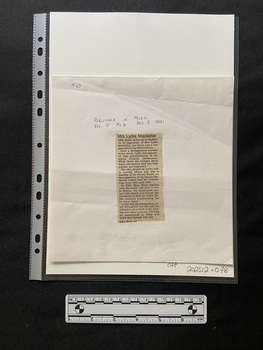 A column of printed type with a bold print heading and five short paragraphs, that has been cut from a newspaper and attached to a backing card with tape at the top and the bottom of the clipping.