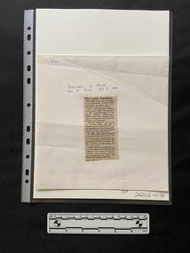 A column of printed type with a bold print heading and five short paragraphs, that has been cut from a newspaper and attached to a backing card with tape at the top and the bottom of the clipping.