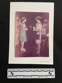 Coloured photograph of two Army Nurses meeting Queen Elizabeth II in the Army mess hall.