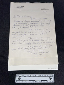 Handwritten letter in blue ink with a letterhead printed in black across the top that reads E. Mervyn Harris. The corresponding address is printed in the top right corner.The letter is attached to backing card. It is lies on top of a pile of typed A4 pages.