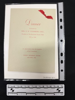 A pale grey folded card with red printed text and a red ribbon tied in the upper right hand corner
