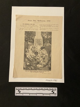 The first page of a two page article. There is a heading in bold type, followed by two short columns of text and a large photograph of two women laying a wreath at a war memorial.