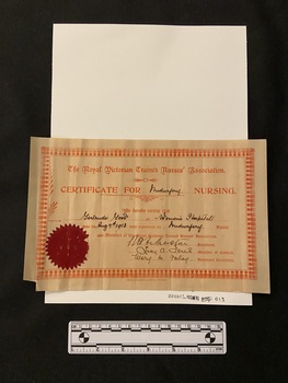 Certificate stamped in red ink on pale brown paper, details are handwritten in black ink. There is a burgundy sticker seal in the lower left corner.