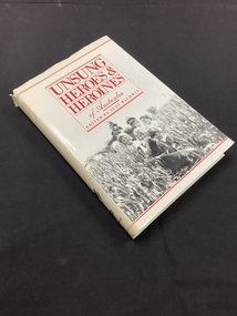 White hardcover book covered in a white dust jacket. The dust jacket has a red box, with the heading printed in red text inside, at the top half of the page. The lower half of the page shows a black and white photo of a man and woman with six children standing in front of them and another child sitting on the man's shoulders, they are all standing in a field of tall crops. There are two horizontal red lines running along the top and bottom of the cover.