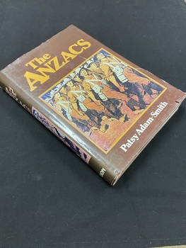 Brown hardcover book with a brown dust jacket. Both the front cover and spine of the dust jacket show the title and a brown and white drawn image of lines of soldiers marching in uniform.