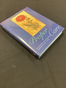 Hardback book with a dark blue dustjacket. Along the spine the title is printed in light aqua script, followed by the printed text of the sub-title and author's name, there is a mark on the bottom of the spine where a sticker has previously been removed.
The front shows an image of a red flower with some greenery set in a light brown rectangle, below which the title is again printed in light aqua script.